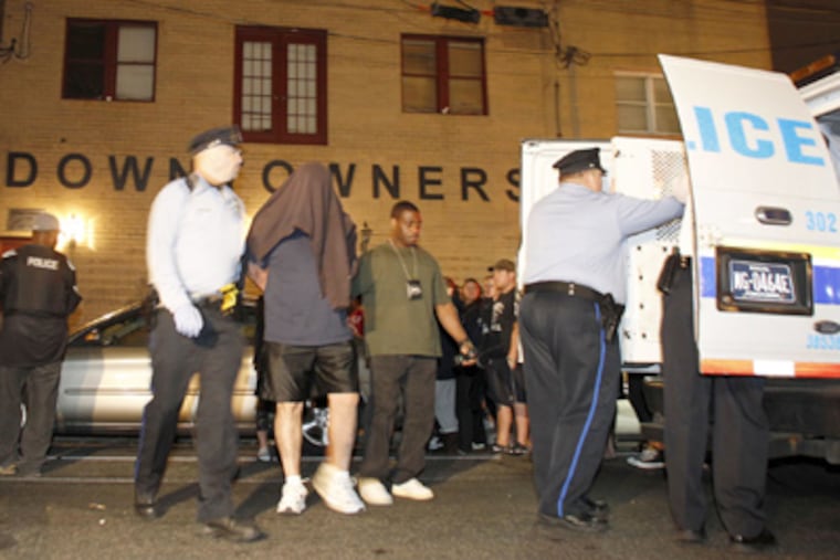 Police escort a man from the Downtowners clubhouse after the raid. Arrested were 13 people, including 10 women and two executives of the Fancy Brigade. (Yong Kim / Staff Photographer)