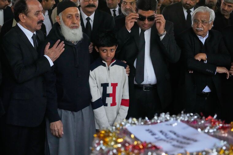 Mourners comfort Yahya Zubair, the son of lawyer Zubair Aslam Ghumman, who was killed in Tuesday's suicide bombing outside the gates of a district court in Islamabad, Pakistan.