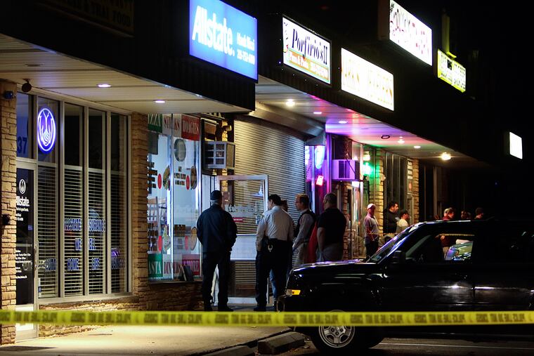 Investigators gather outside the Porfirio's II Pizza & Pasta, in Levittown Pa, Tuesday Nov. 15, 2016, after one man was wounded and a second killed during an attempted robbery.