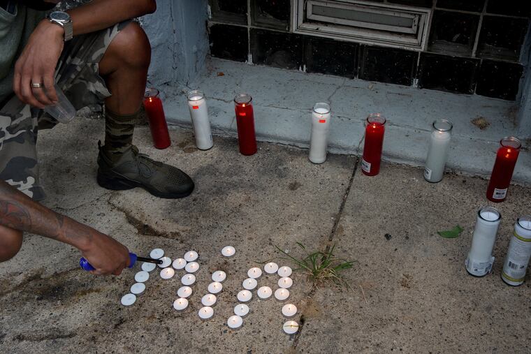 A neighbor on North Simpson Street in West Philadelphia prepares for a candlelight vigil for 7 year-old Zamar Jones last week. Sometimes called "Mir" for short, Jones died earlier in the day after being shot while playing on his front porch.