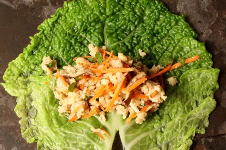 Start with a blanched cabbage leaf, tough stem end trimmed so the finished roll is fork-tender. Place filling on each leaf and get ready to roll. This will be Sesame-Ginger Poached Chicken & Rice Stuffed Cabbage Rolls.