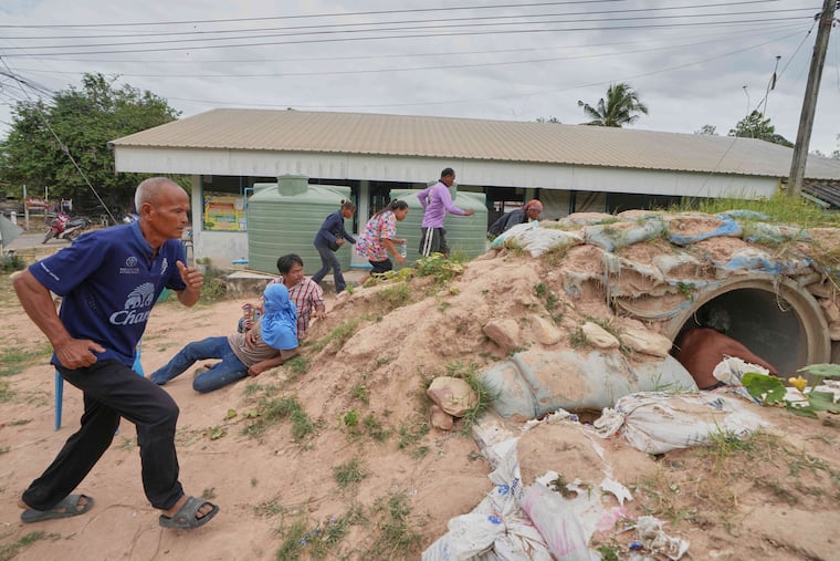 Village security volunteers and residents run into shelter when blasts sounded too close in Buriram province, Thailand, Friday, Dec. 12, 2025, following renewed border conflict between Thailand and Cambodia.