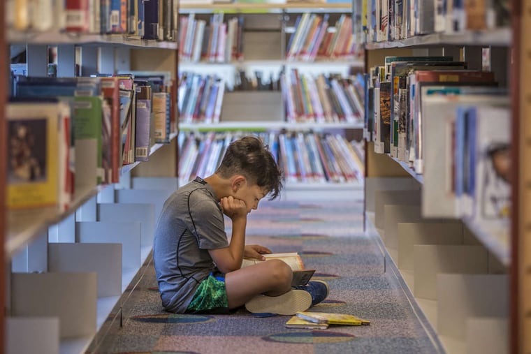 Judah Niv, 8, sits on the floor of the second floor children's book section of the Cherry Hill Public Library.