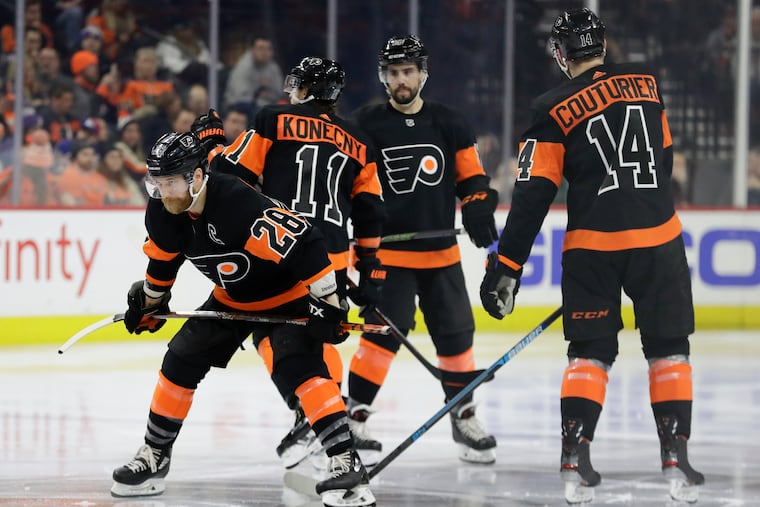 Team On His Back: Claude Giroux waits for the start of the third-period face-off against the Rangers on Monday as teammates Travis Konecny, Matt Niskanen and Sean Couturier mill about.