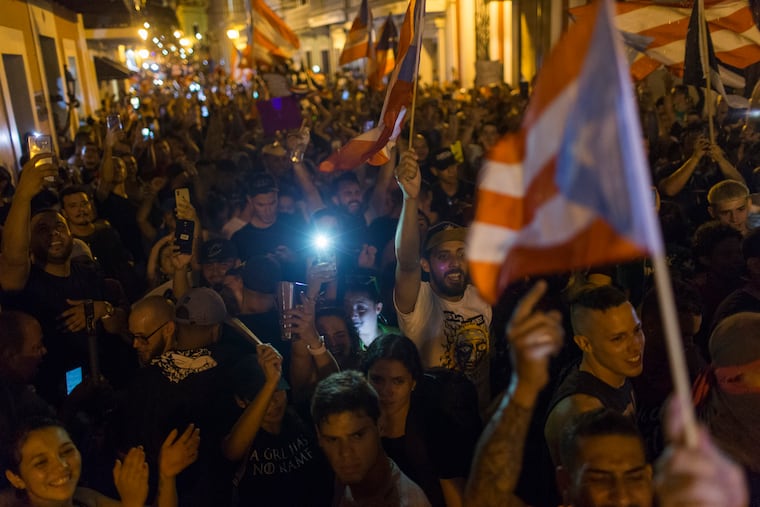 People celebrate outside the governor's mansion La Fortaleza, after Gov. Ricardo Rossello announced that he is resigning Aug. 2 after weeks of protests over leaked obscene, misogynistic online chats, in San Juan, Puerto Rico, Wednesday, July 24, 2019.