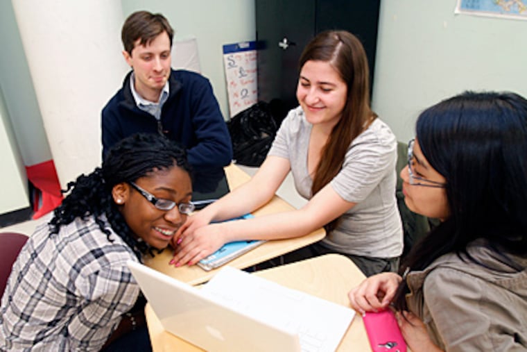 Students Newon Dennis (left) and Elona Myftaraj (third from left) use a laptop to show off an image of a dress they designed and produced to Rich Sedmak, StartupCorps cofounder, and fellow student Gisela Giolafina. (Charles Fox / Staff Photographer)