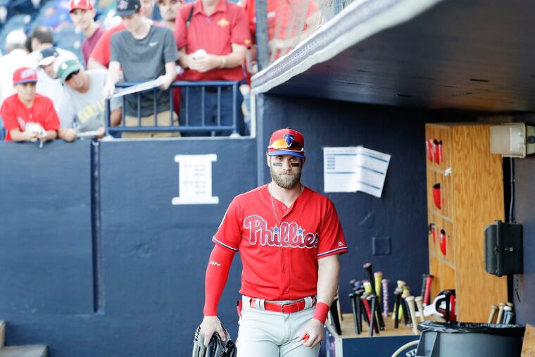 Bryce Harper walks through the dugout at the Yankees' spring-training facility as fans lean over to try to get an autograph.