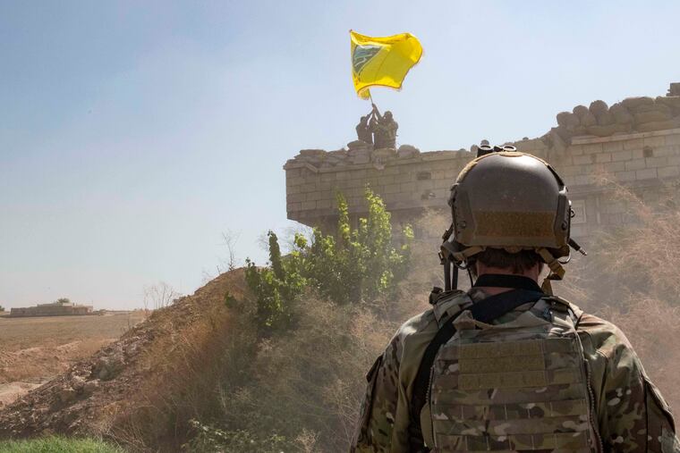In this Sept. 21, 2019, photo, released by the U.S. Army, a U.S. soldier oversees members of the Syrian Democratic Forces as they demolish a Kurdish fighters' fortification and raise a Tal Abyad Military Council flag over the outpost as part of the so-called "safe zone" near the Turkish border. (U.S. Army photo by Staff Sgt. Andrew Goedl via AP)