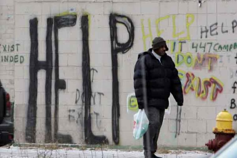 A pedestrian walks by graffiti in downtown Detroit in a Dec. 12, 2008, file photo. (AP Photo/Carlos Osorio, File)