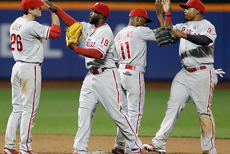 Chase Utley (26), Tony Gwynn (19), Jimmy Rollins (11) and Marlon Byrd (3) celebrate after a baseball game against the New York Mets, Friday, May 9, 2014, in New York. The Phillies won 3-2. (Frank Franklin II/AP)