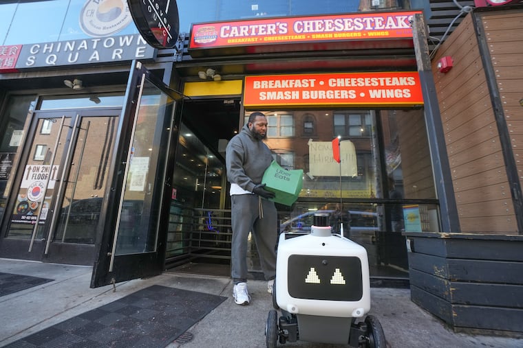 Lavelle "Garci" Peterkin, owner and CEO of Carter's Cheesesteaks by Garci, demonstrates how the Uber Eats food delivery robot works.