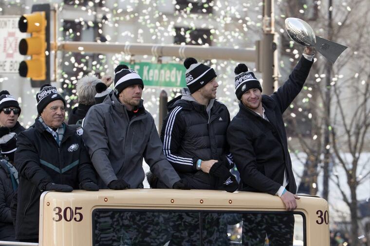 Philadelphia Eagles NFL football team quarterback Carson Wentz, right, holds up the Vince Lombardi trophy as he rides with fellow quarterbacks Nate Sudfeld, center right, Nick Foles, center left, and team owner Jeffrey Lurie, left, during a Super Bowl victory parade, Thursday, Feb. 8, 2018, in Philadelphia. The Eagles beat the New England Patriots 41-33 in Super Bowl 52.