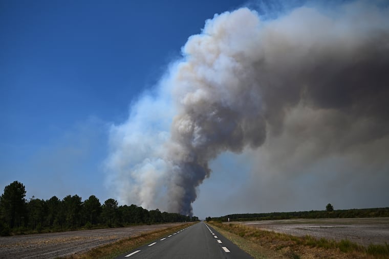 Smoke rises above a road near Saint-Jean-d'Illac, during wildfires in southwestern France, Tuesday, July 28, 2026.