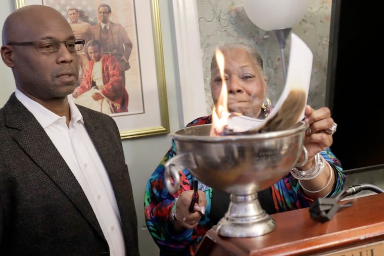 West Philadelphia Cultural Alliance assistant treasurer Clayton Slater and then WPCA executive director Vernoca L. Michael watch as the ceremonial mortgage document burns during the mortgage-burning ceremony at the Paul Robeson House on Jan, 25, 2020.