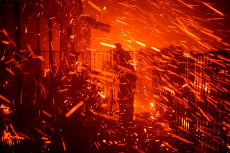 Jerry Rowe uses a garden hose to save his home on Beaufait Avenue from the Saddleridge fire in Granada Hills, Calif., Friday, Oct. 11, 2019.
