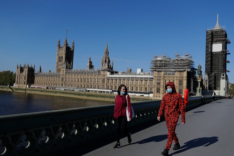 People wear masks as they walk near Britain's Houses of Parliament as the country is in lockdown to help curb the spread of coronavirus.