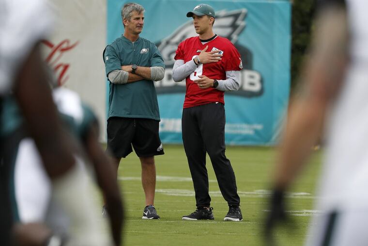 Eagles offensive coordinator Frank Reich talks with Nick Foles during Saturday’s workout. Foles sat out again on Sunday.