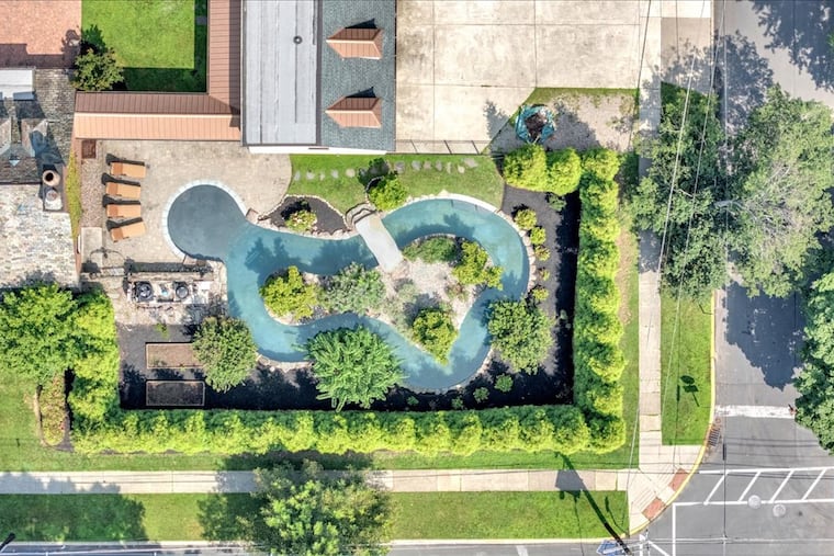 An aerial view of the lazy river-style pool, which has a landscaped center island accessible via a bridge.