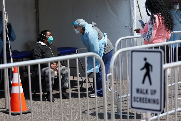 Jackie Scott (left) talks to a medical worker as she tries to get a coronavirus test in Camden on Wednesday. Scott, who said her mother had COVID-19 but has recovered, was not able to get tested at the site because she had no symptoms and did not have a referral from a doctor.