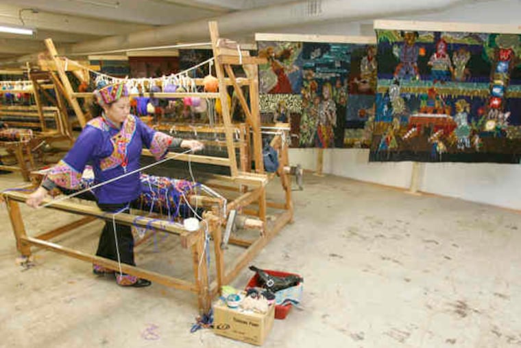 Weaver Li Cheng-Feng works on a loom, with exhibited tapestries hanging in the background. Five weavers from Hunan province are carrying out the project conceived by artist Cai Guo-Qiang and named by him "Time Flies Like a Weaving Shuttle."