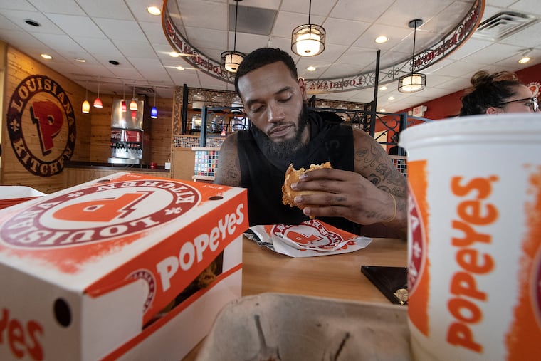 76er player Mike Scott eats the new spicy chicken sandwich at Popeye's located on S. Front street, Philadelphia. Tuesday, August 20, 2019.
