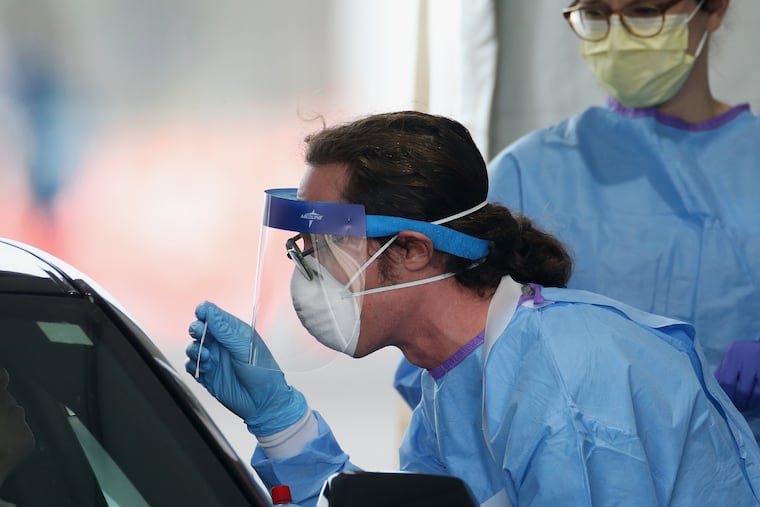 Stephen Bonett, a nurse and Philadelphia Medical Reserve Corps volunteer, administers a nasal swab to a driver at the city's coronavirus testing site next to Citizens Bank Park in South Philadelphia on Friday, March 20, 2020. The site, which opened Friday afternoon, is the first city-run drive-through location where people can be swabbed to determine if they have the coronavirus. At the time of opening, it was only for people with symptoms who are over 50 and healthcare workers with symptoms.
