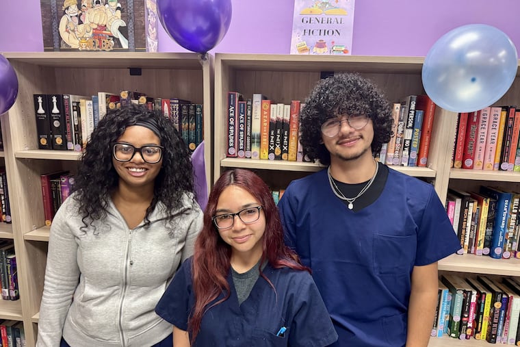 Students Ryan King, Angie Medina, and Christian Toro — founding members of the DreamEscape Library at Kensington Health Sciences Academy — stand in front of some of the library's new books at its grand opening.