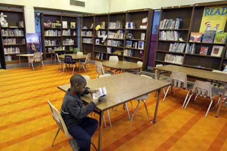 Rawle Williams, 7, a first-grader at the Richard R. Wright Elementary School, spends a few minutes in the school's unstaffed library. (Elizabeth Robertson / Staff Photographer)