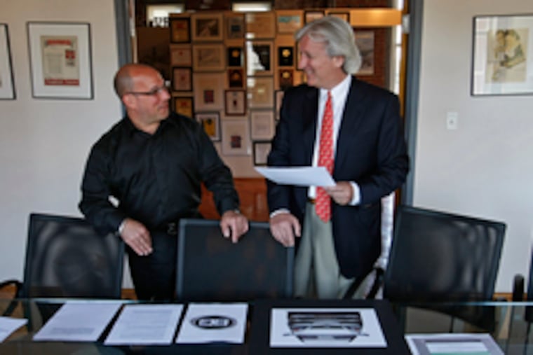 Barry D. Bernsten (right) and David Neff of Neff Associates talk about logo designs for the low-speed, battery-electric cars Bernsten says he will have on the road by fall.