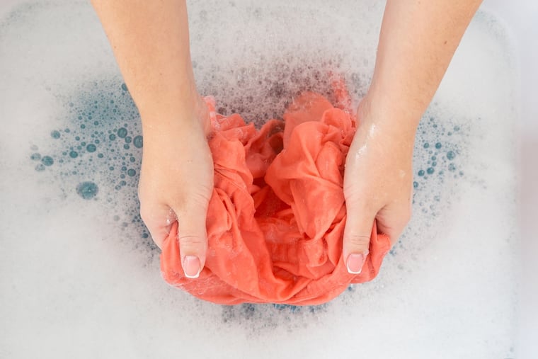 Hand-washing a garment in a sink. (Photo: Tribune News Service)