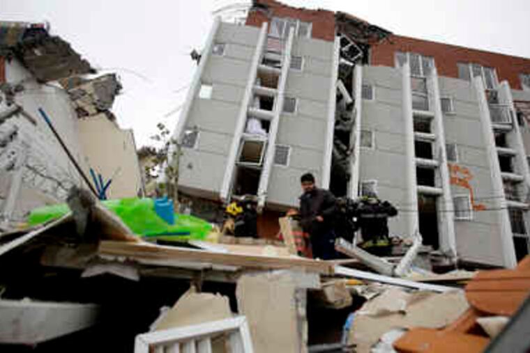 Relatives and firefighters search in Concepcion, Chile, where an apartment building toppled onto its side.