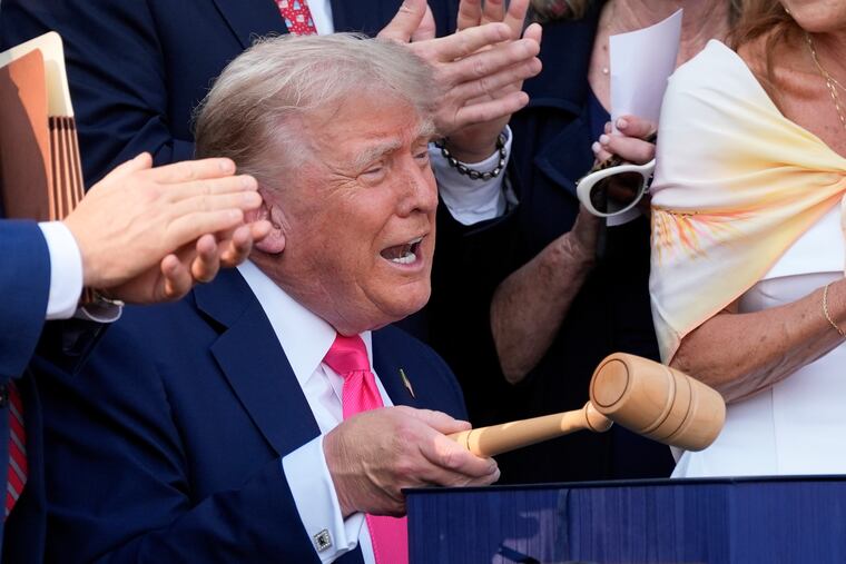 President Donald Trump bangs a gavel gifted to him by House Speaker Mike Johnson after signing the so-called "Big Beautiful Bill" of tax breaks and spending cuts at the White House on July 4.