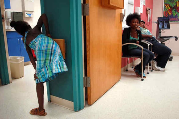 At Shriners Hospital in Philadelphia, Sarah Maurice, 8, hops without a crutch as another Haitian girl, Chantal Mori, 17 (right), smiles at her.