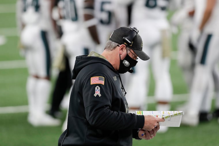 Looking for answers? Doug Pederson peers at his play chart during Sunday's 27-17 loss at the Giants.