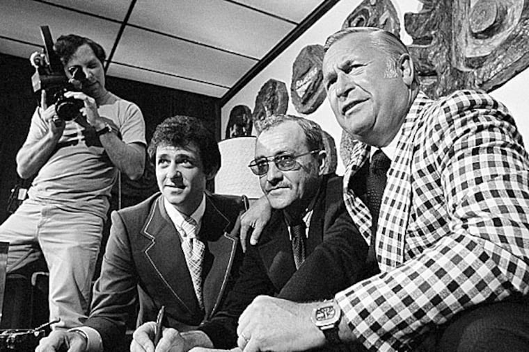 Flyers head coach Fred Shero (center) signs a sample contract for photographers as Mark Stewart (left) and general manager Keith Allen look on. (Brian Horton/AP file photo)