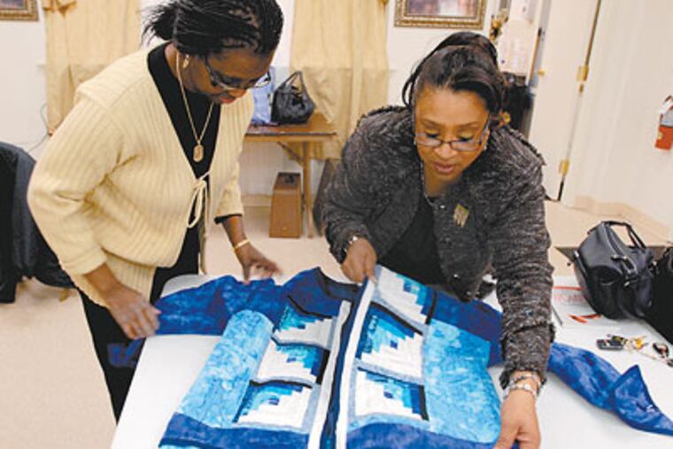 From the left, Lois Jones and Edna White look at Jones' log cabin blockjacket constructed as part of the black history month quilts project at Second Baptist Church. (Ron Taver / Staff Photogapher)