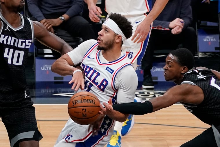 Seth Curry is fouled by Sacramento Kings guard De'Aaron Fox (right).