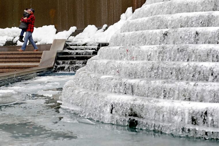 Kenneth Freeman, carries his daughter Alora, 8, as they visit a frozen water fountain downtown in Atlanta, Wednesday, Jan. 3, 2018. A brutal winter storm scattered a wintry mix of snow, sleet and freezing rain from normally balmy north Florida up the Southeast seaboard Wednesday, adding to the misery of a bitter cold snap.