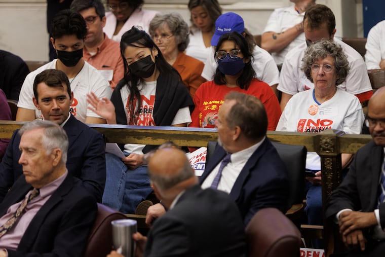 An activist with the Save Chinatown Coalition waves in the direction of City Councilmember Mark Squilla, foreground, during a September session.