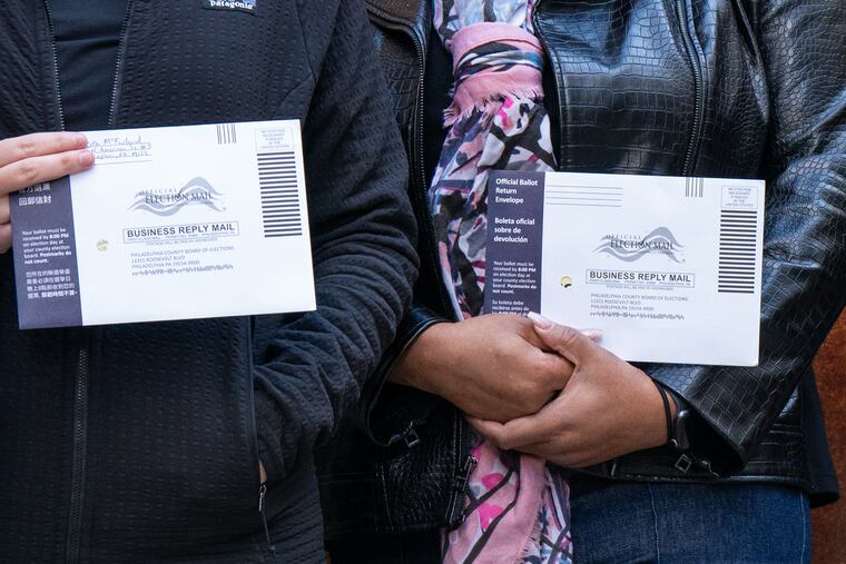 Chelsea McFarland, left, French horn, and Nicole Jordan, right, Principal Librarian, hold their absentee ballots at City Hall, as musicians and Staff of the Philadelphia Orchestra deliver Absentee Ballots to City Hall before Departing on a tour of China, Tuesday.