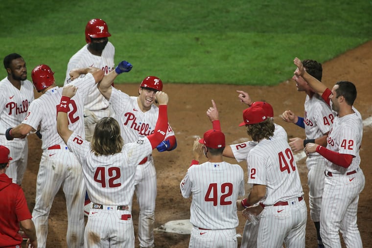 Scott Kingery celebrates his walk off three-run homer again the Braves with teammates in the 11 inning.