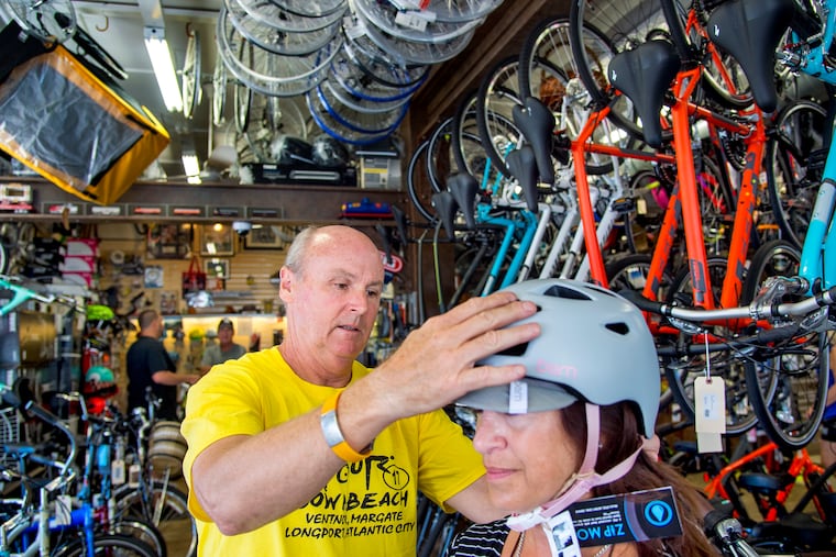 FILE PHOTO: Mike Wiesen, owner of AAAA Bike Shop in Ventnor helps Jennifer Seligsohn with her helmet September 2, 2018.