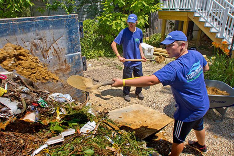 Student volunteers (right) Ryan Koch, 15, and Elijah Keliwitz, 16, both of Gilead, Nb., shovel dirt and debris into a dumpster at a home damaged by Hurricane Sandy on Cedar Berry Land, Toms River, July 23, 2014. ( DAVID M WARREN / Staff Photographer )