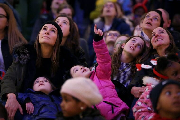 Karen Builione, top left, watches the holiday light show with her daughters Isabella, 7, in blue, and Francesca, 4, in pink, in Macy's.