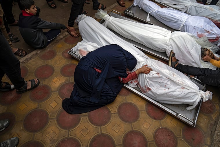 A woman mourns the covered bodies of her child and her husband killed in an Israeli army bombardment of the Gaza Strip, in the hospital in Khan Younis, on Tuesday.