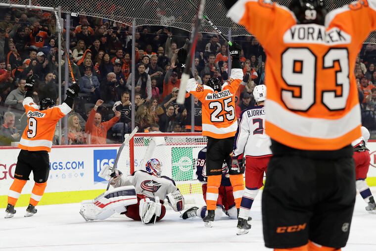 Flyers left winger James van Riemsdyk raises his arms after scoring a third-period goal as teammates Ivan Provorov (9) and Jake Voracek (93) also celebrate. The goal tied the score at 4-4 and the Flyers finished with a wild 7-4 comeback victory.