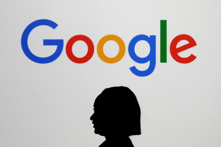 A woman walks by a giant screen displaying the Google logo at an event at the Paris Google Lab on the sidelines of the AI Action Summit in Paris, Feb. 9, 2025.