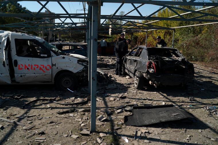 Police officers work at a site where several cars were damaged after a Russian attack in Zaporizhzhia, Ukraine, Saturday, Oct. 15, 2022.