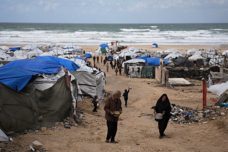Palestinians receive donated food at a temporary camp for displaced people, on the beach near the port of Gaza City, Sunday, Dec. 28, 2025.