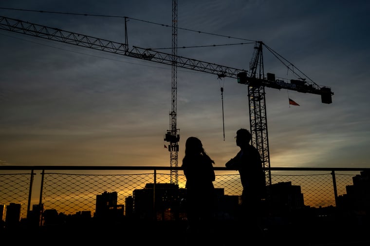 The sun setting behind construction cranes in University City in August, seen from the rooftop urban park Cira Green. City Council is considering legislation that would require breaks for the operators of tower cranes like the one pictured.